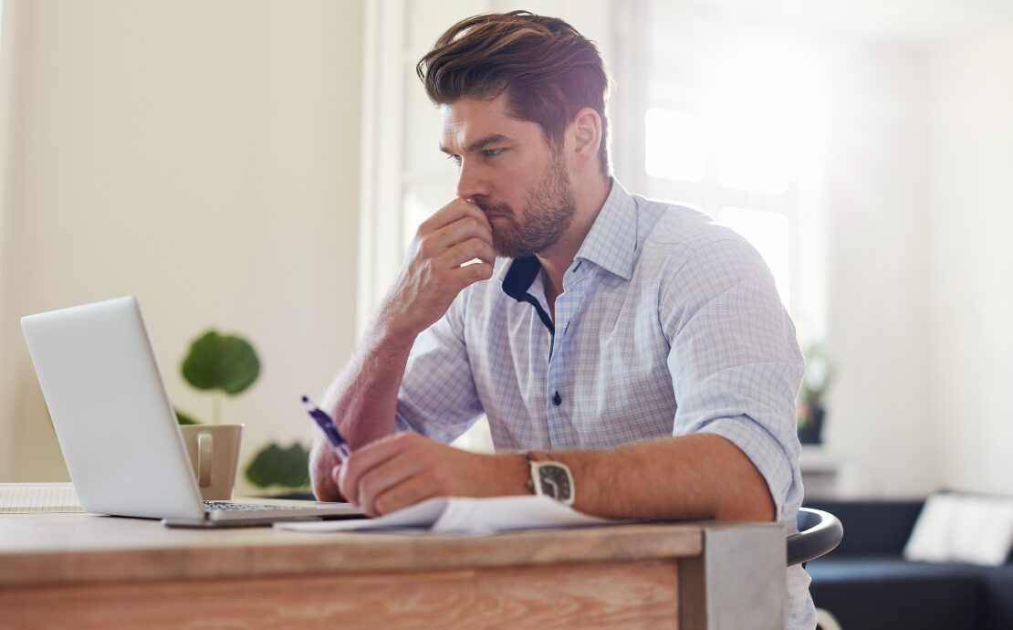 Man looking at laptop with a thoughtful expression