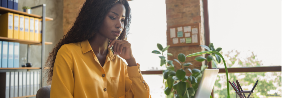 Woman looking thoughtfully at laptop screen